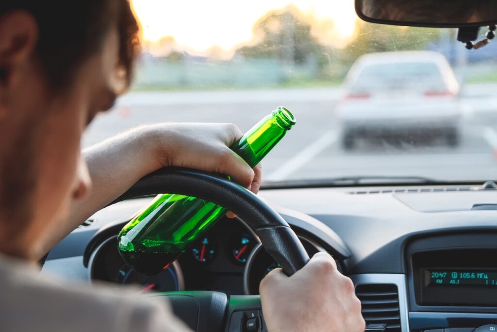 a man driving under the influence with a beer in hand