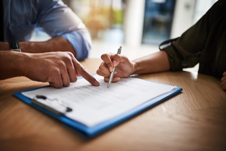 two individuals reading over and signing legal document