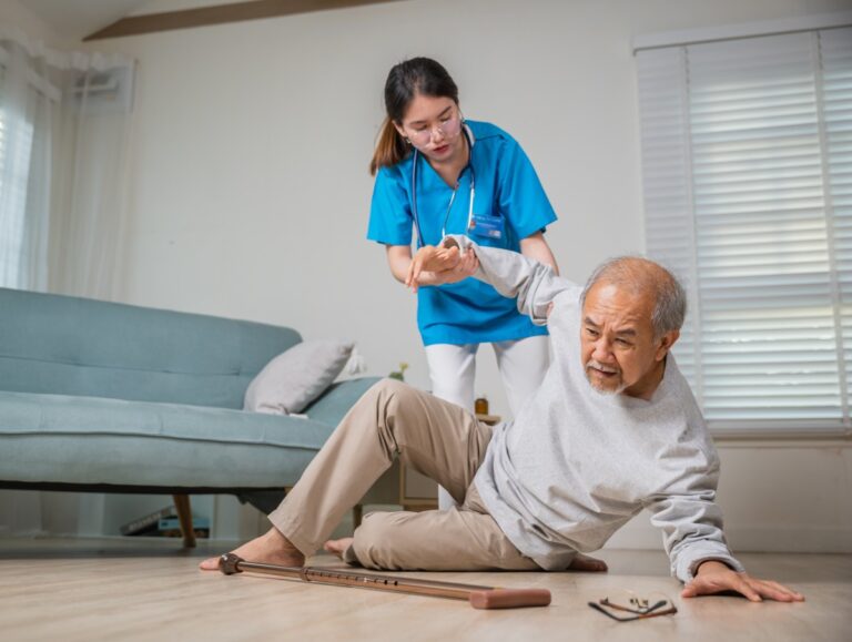 a man who has fallen in a nursing home and is being assisted by a nurse